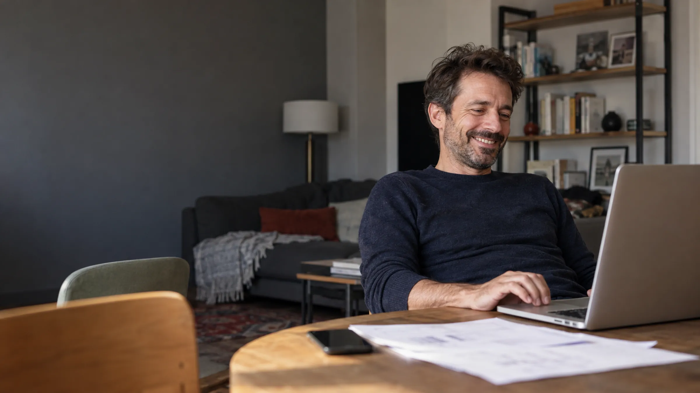 Indépendant détendu et souriant devant son ordinateur, chez lui