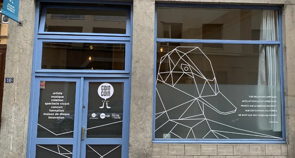 Vitrine des locaux de Coin Coin Productions, un canard dessiné au trait sur la baie vitrée